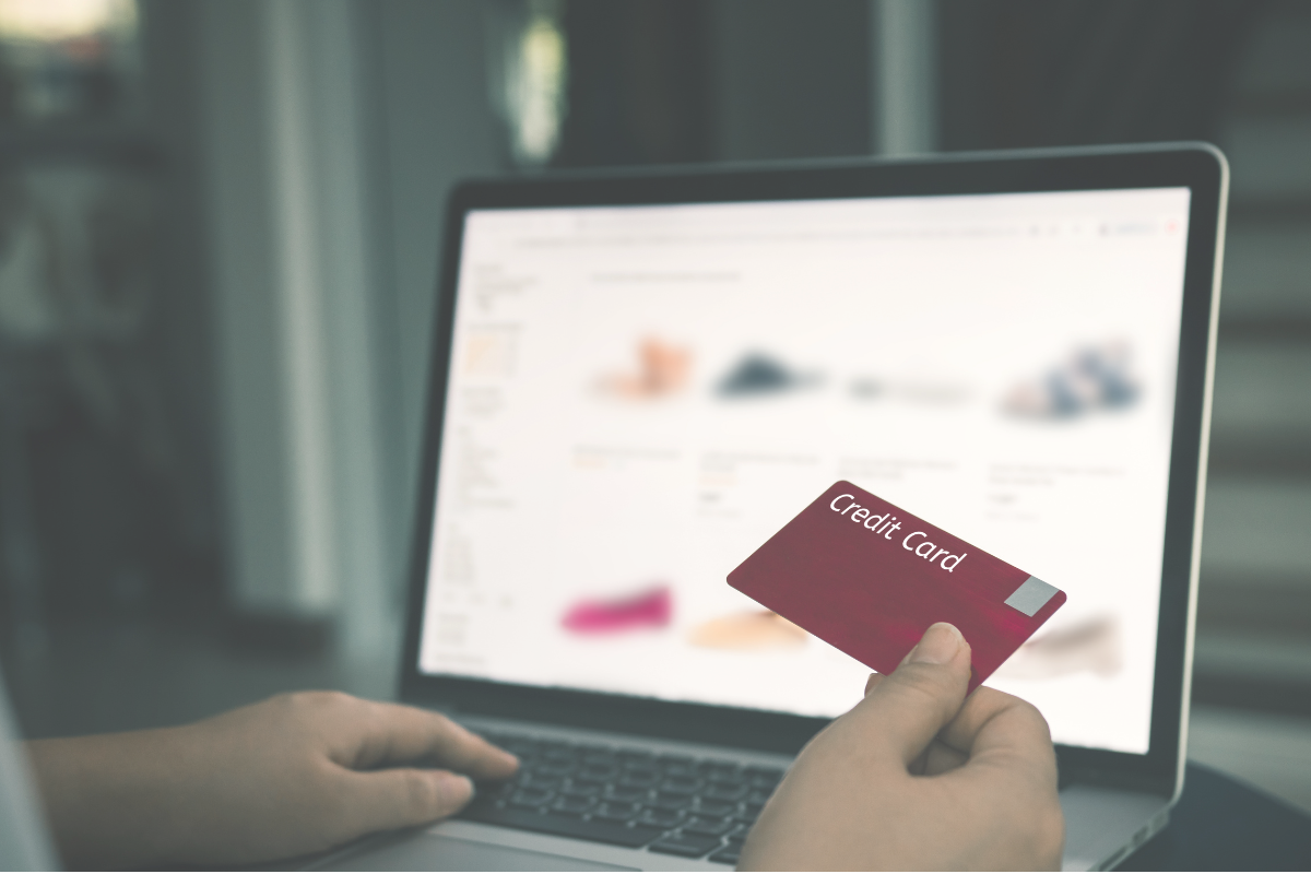 A person holding a credit card while shopping online on a laptop
