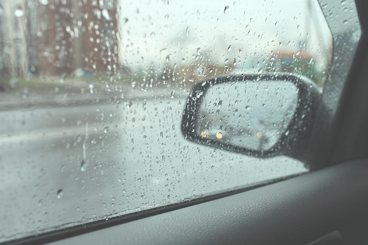 Rain covering a car window and making the view outside difficult to see