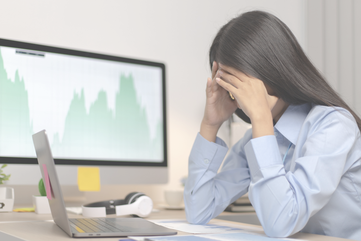 An office worker sitting at a desk and holding their head in their hands