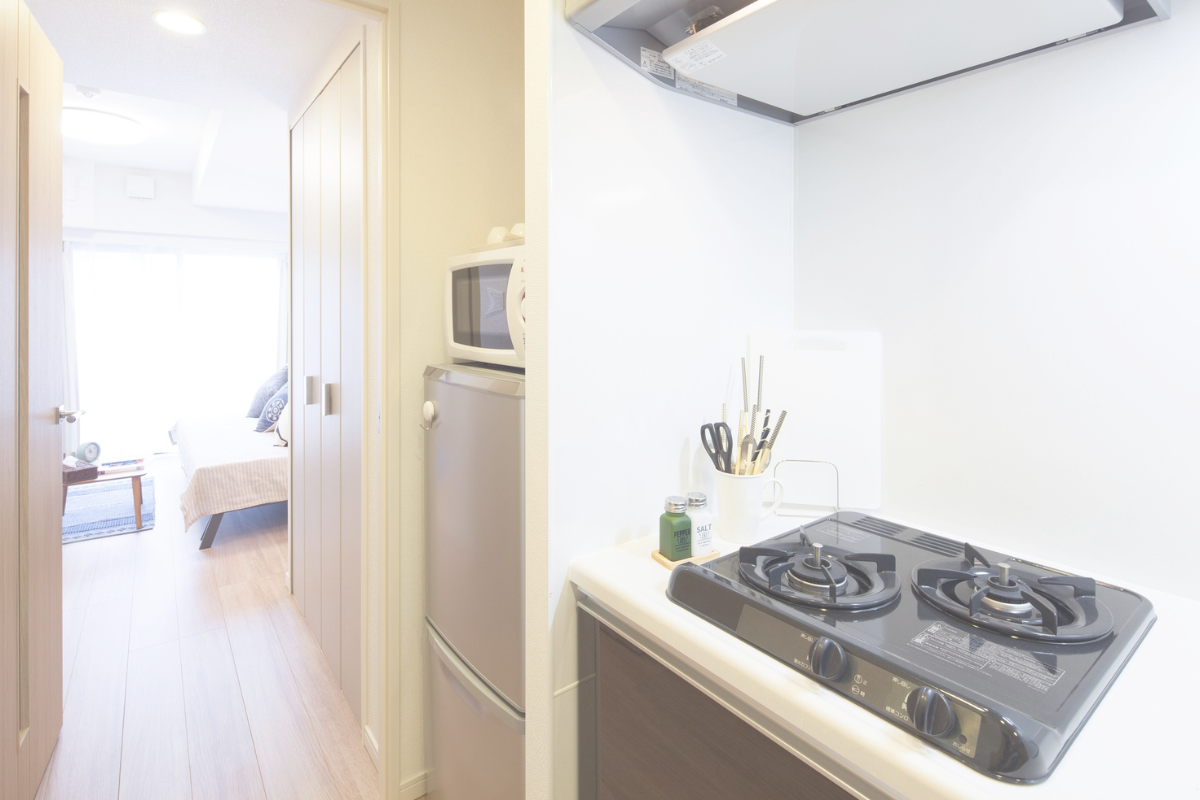 A small apartment interior with a compact kitchen and gas stove