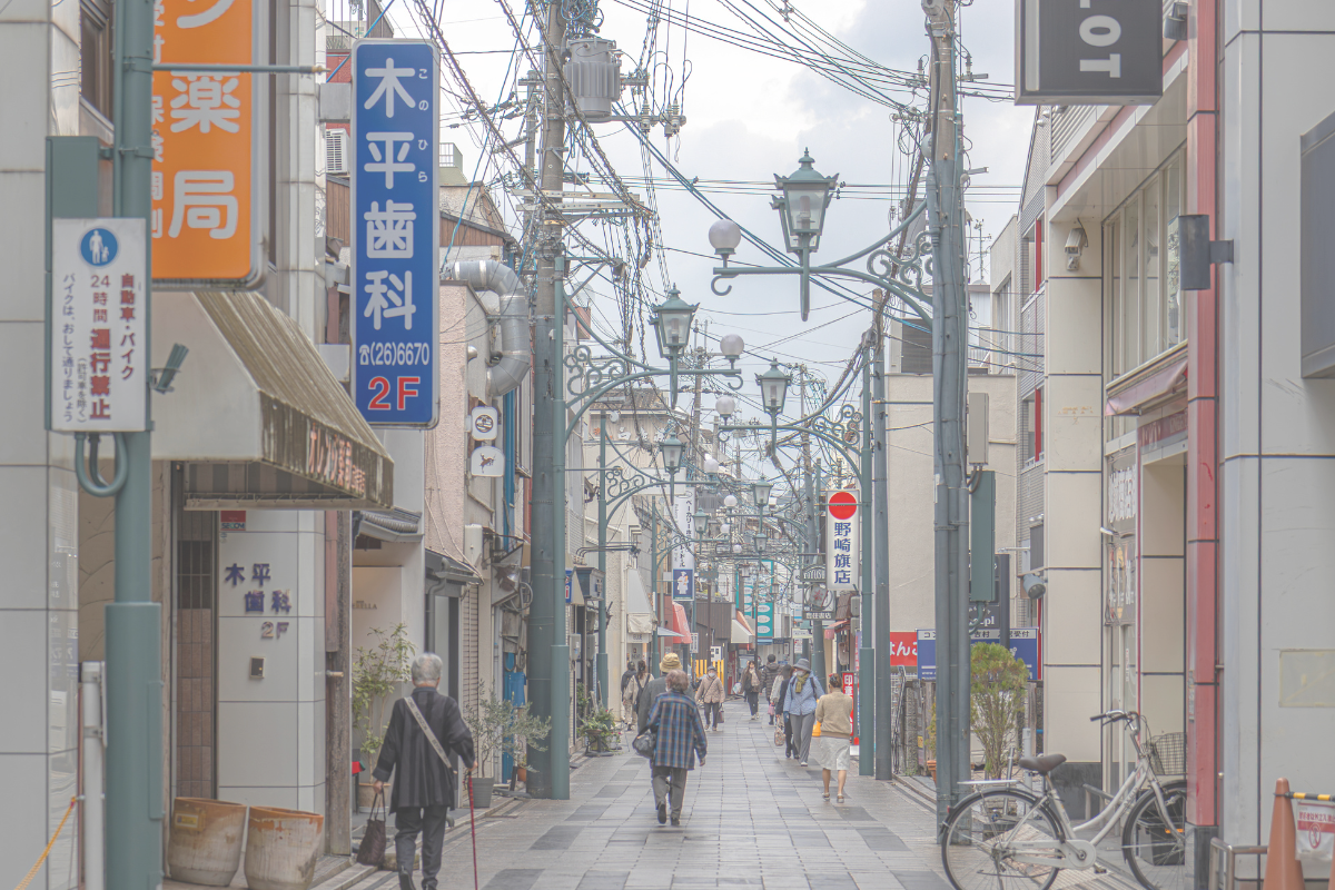 A quiet Japanese street with small shops and people walking along the road