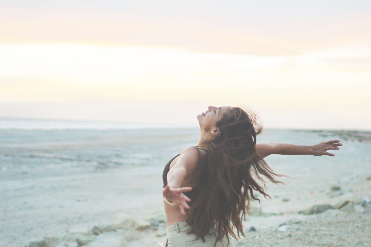 Woman standing by the sea with her arms outstretched
